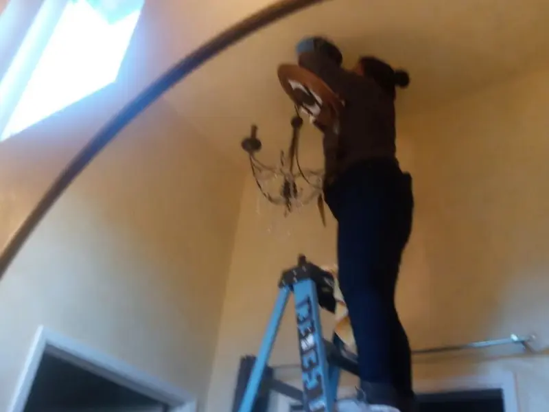 Electrician installing a chandelier in a Bunker Hill Village residence